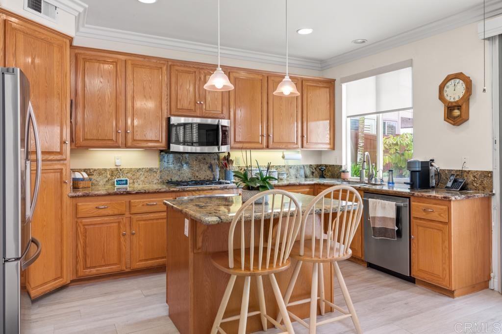 7301 Seafarer Place Carlsbad, CA 92011 - Photo 14 of 33 a kitchen with stainless steel appliances granite countertop a stove a sink dishwasher and a refrigerator with wooden floor