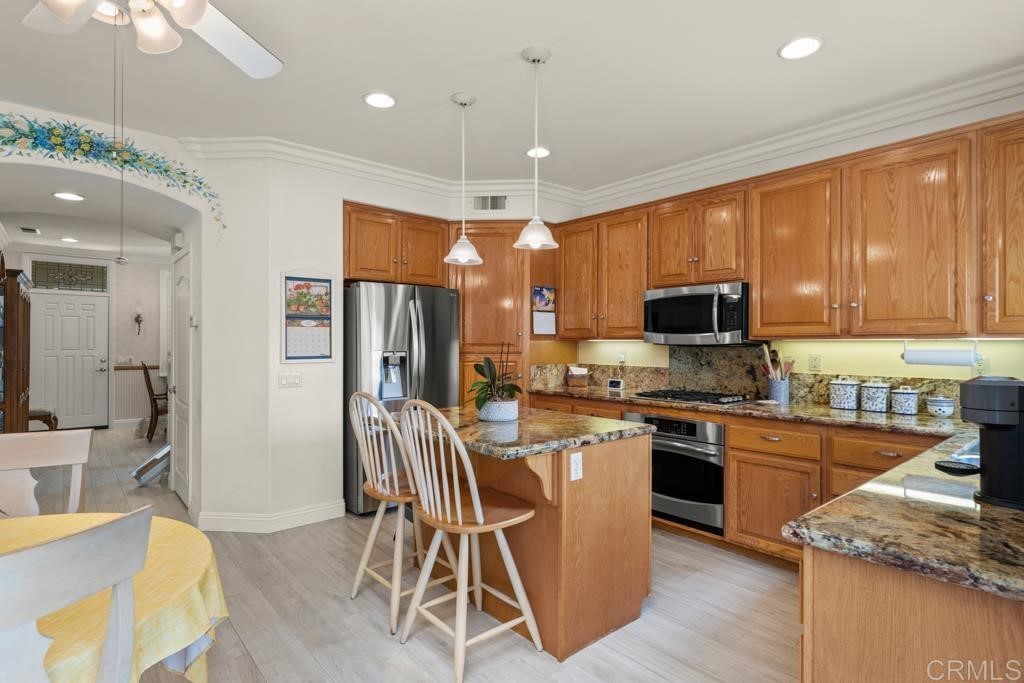 7301 Seafarer Place Carlsbad, CA 92011 - Photo 15 of 33 a kitchen with stainless steel appliances granite countertop a stove top oven a sink dishwasher a dining table and chairs with wooden floor