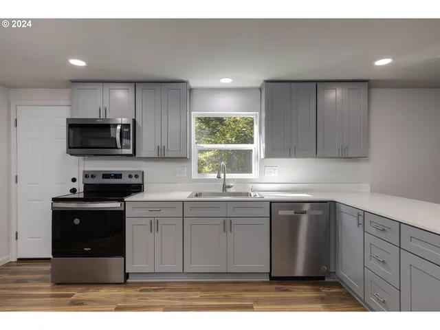 a kitchen with stainless steel appliances granite countertop a stove a sink and a microwave