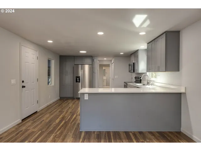 a view of kitchen with stainless steel appliances granite countertop a sink a stove and a wooden floors