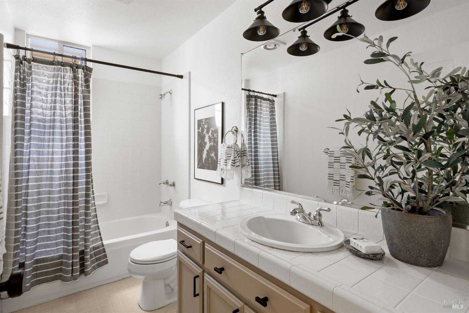 8 Pacific Drive Novato, CA 94949 - Photo 17 of 37 a bathroom with a granite countertop sink a toilet a mirror and shower curtain