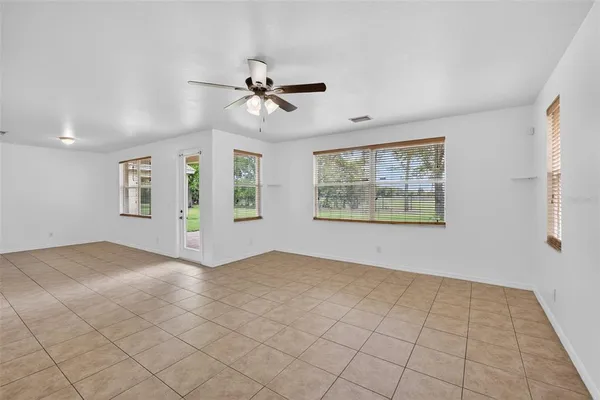 a view of an empty room with a ceiling fan and window