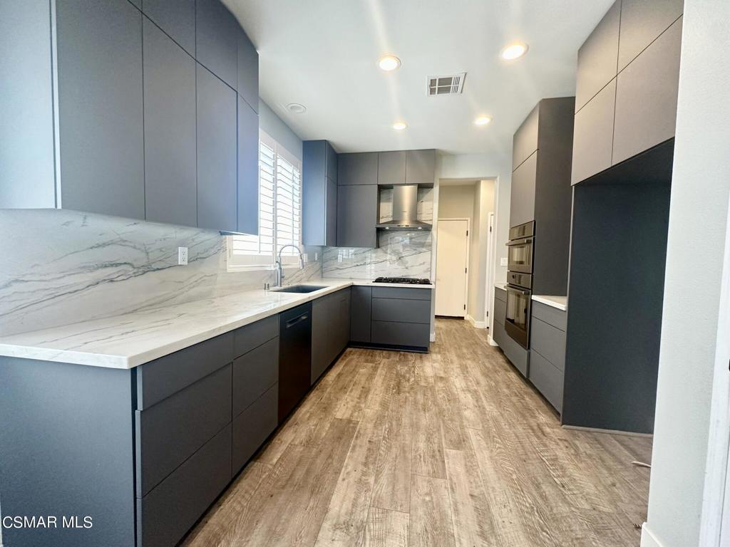 111 Macademia Lane Simi Valley, CA 93065 - Photo 7 of 38 a large kitchen with a large counter top a sink stainless steel appliances and cabinets