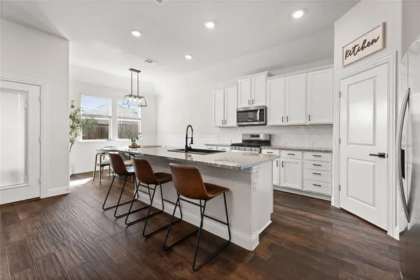 a kitchen with stainless steel appliances granite countertop a white cabinets and wooden floor