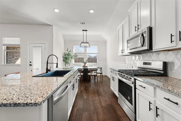 a kitchen with granite countertop a sink stove and cabinets