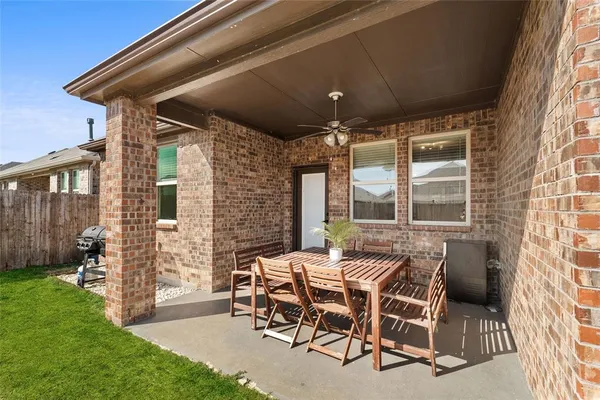 a patio with table and chairs and potted plants