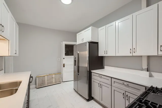 a kitchen with stainless steel appliances granite countertop a refrigerator sink and white cabinets