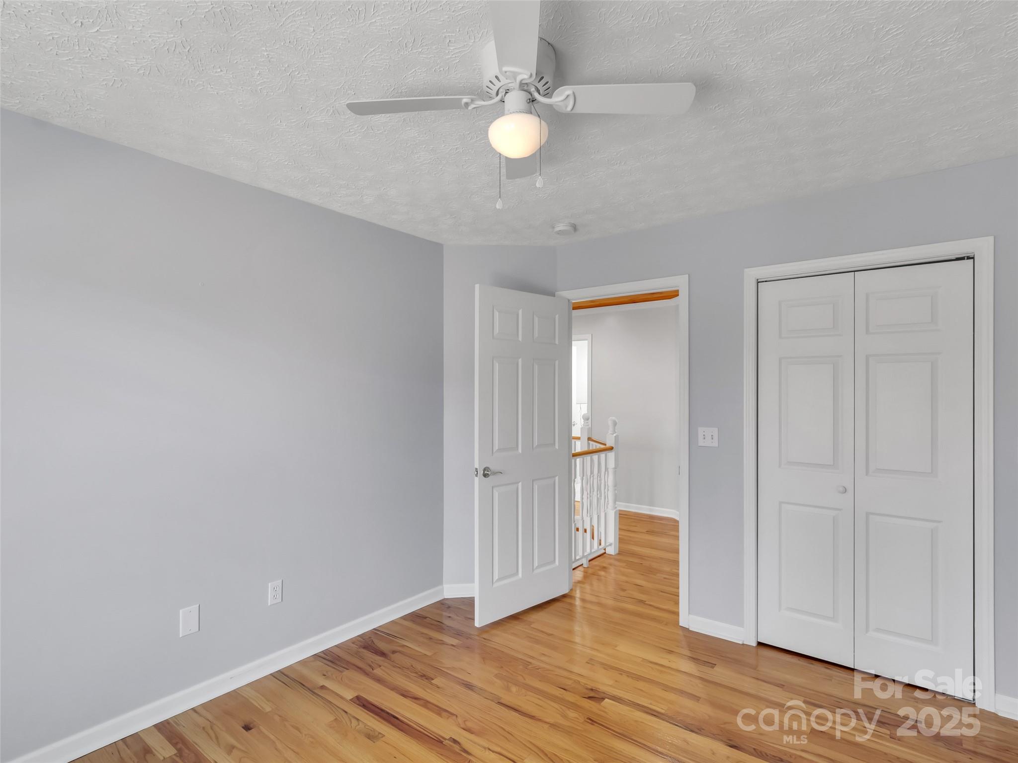 235 Loop Road Clyde, NC 28721 - Photo 16 of 21 a view of empty room with wooden floor and fan
