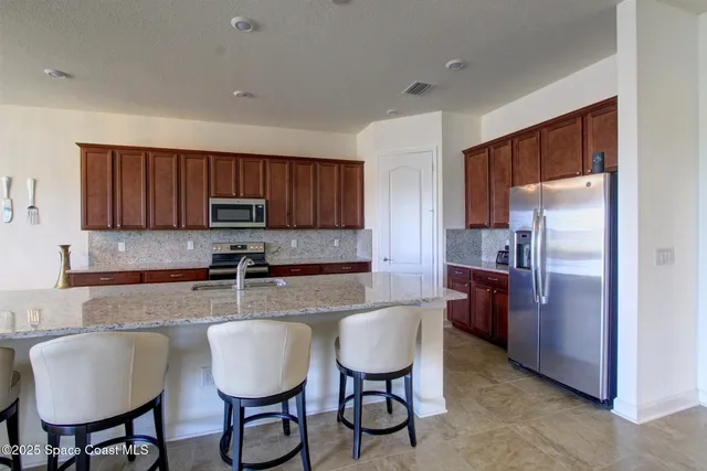 a kitchen with granite countertop a table chairs stove and refrigerator