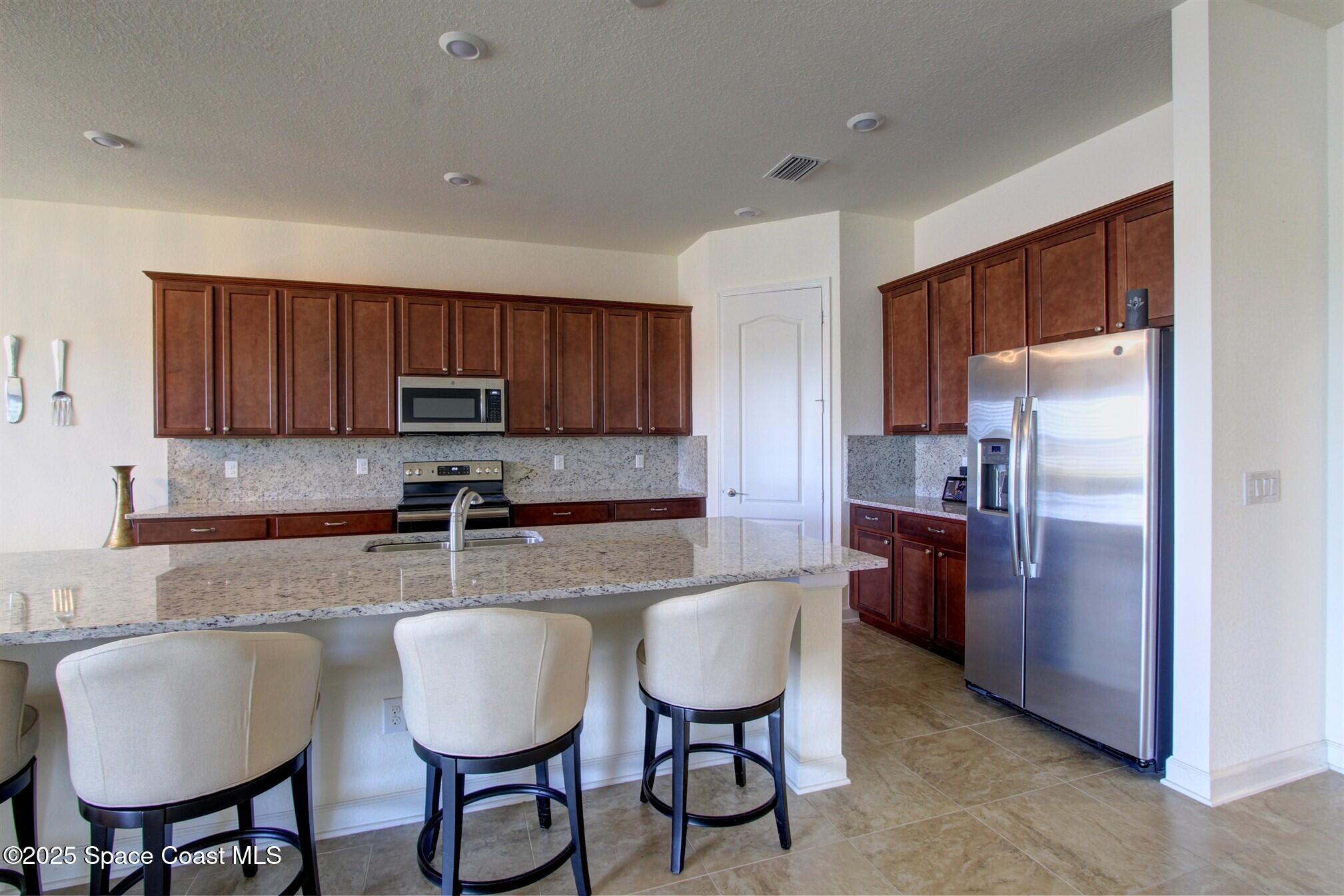 2542 Chapel Bridge Lane Melbourne, FL 32940 - Photo 12 of 44 a kitchen with granite countertop a table chairs stove and refrigerator