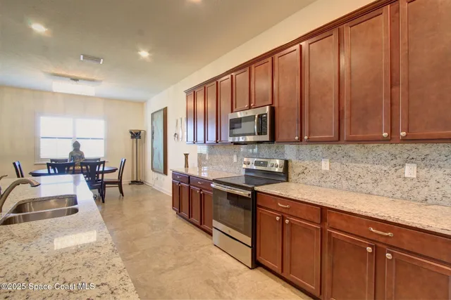 a kitchen with stainless steel appliances granite countertop a sink dishwasher stove and microwave with wooden cabinets