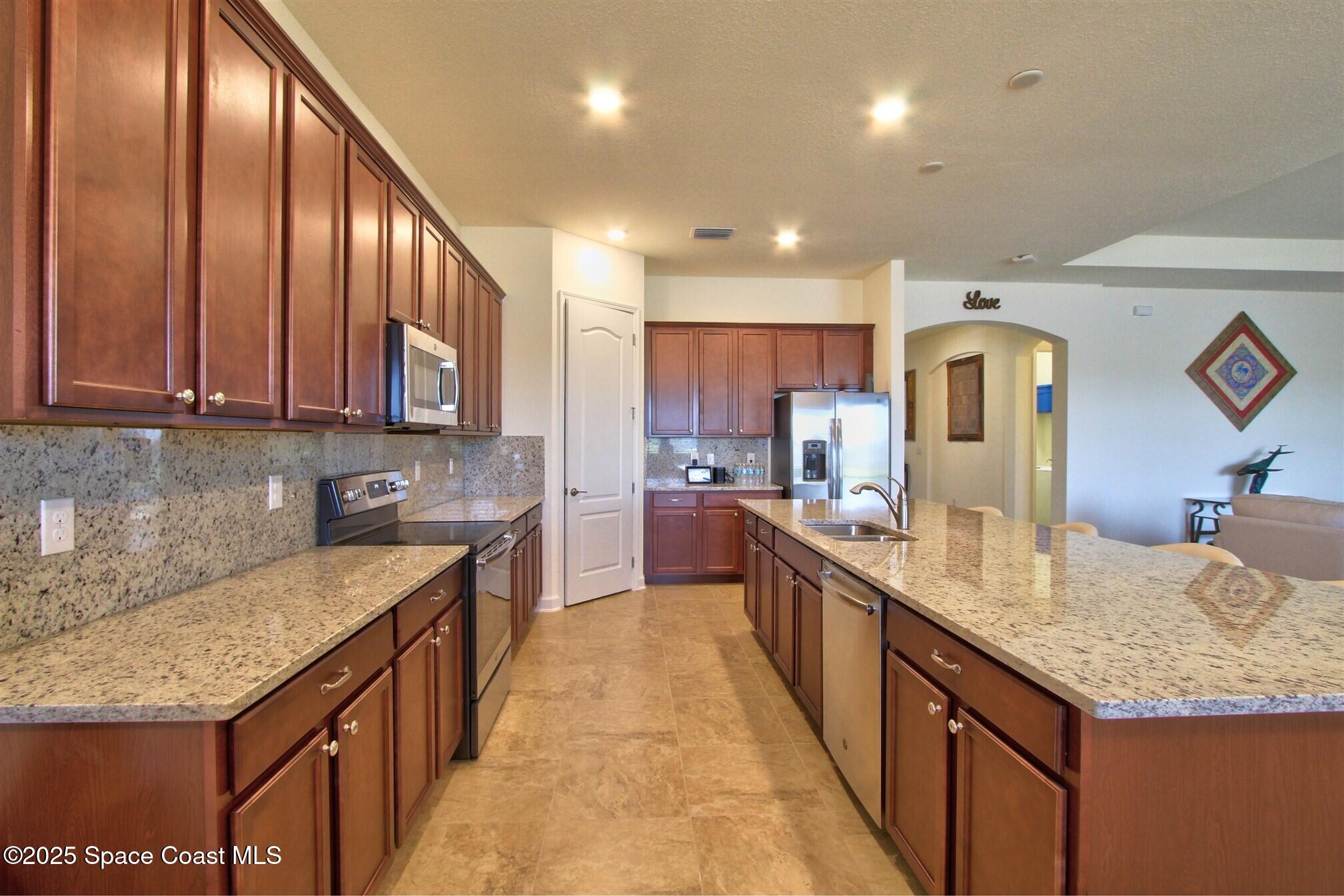 2542 Chapel Bridge Lane Melbourne, FL 32940 - Photo 15 of 44 a large kitchen with granite countertop lots of counter space and stainless steel appliances
