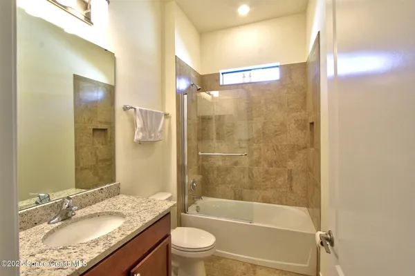 a bathroom with a granite countertop tub sink toilet and shower