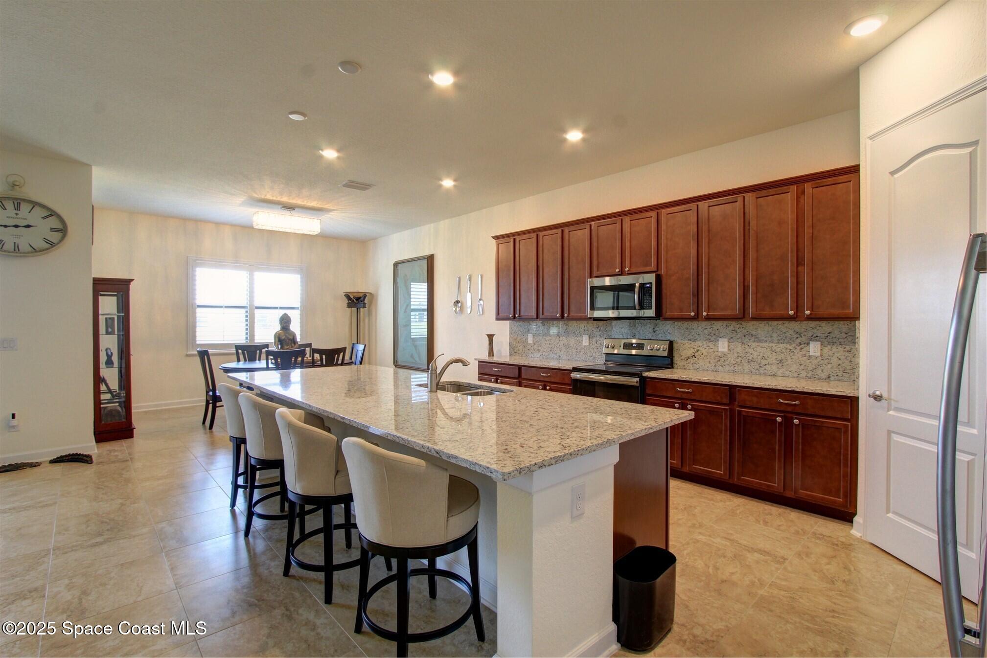 2542 Chapel Bridge Lane Melbourne, FL 32940 - Photo 10 of 44 a kitchen with stainless steel appliances granite countertop a table chairs sink refrigerator and cabinets
