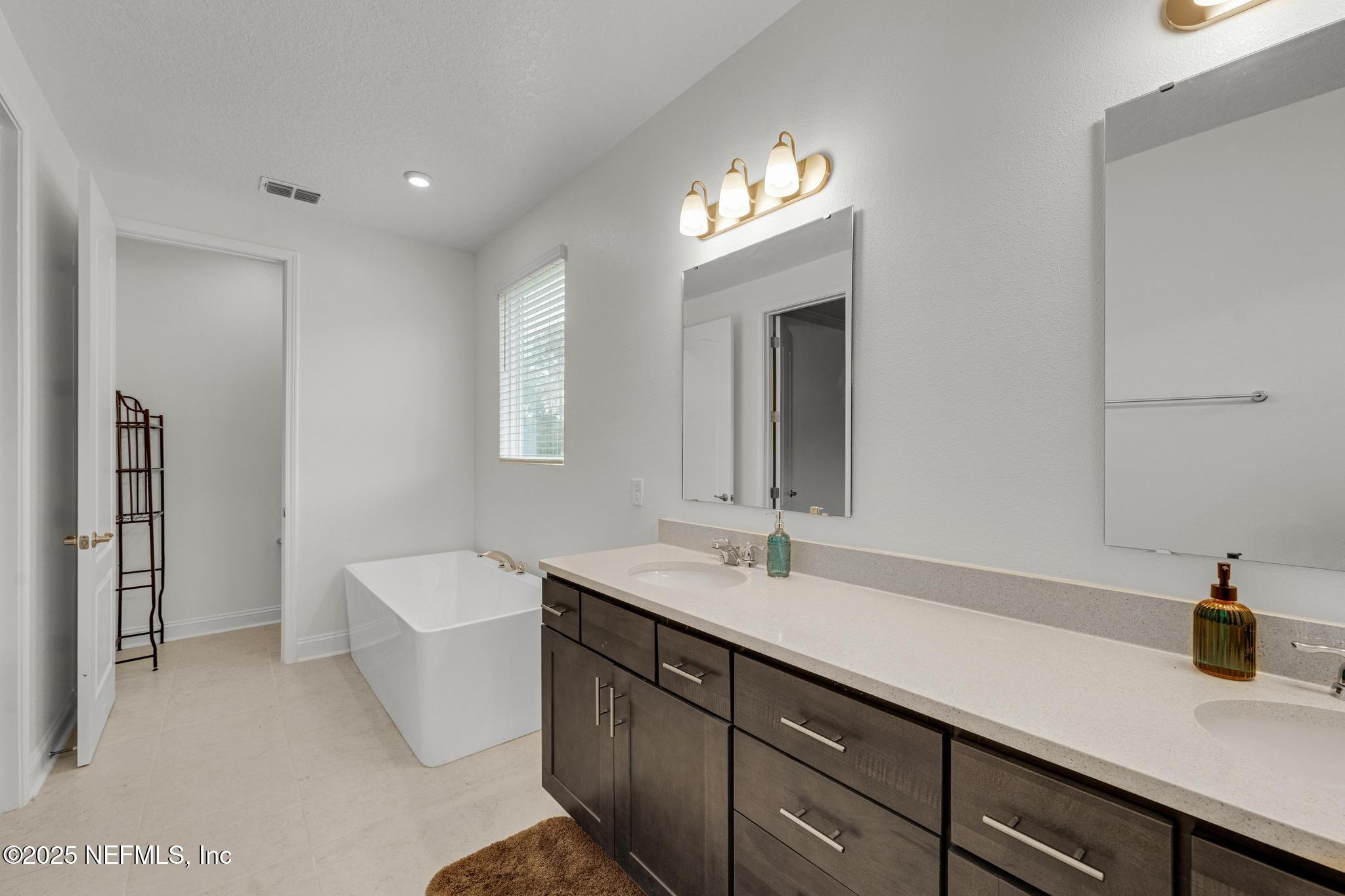 1465 Lake Foxmeadow Road Middleburg, FL 32068 - Photo 39 of 45 a bathroom with a sink a large mirror and a bathtub
