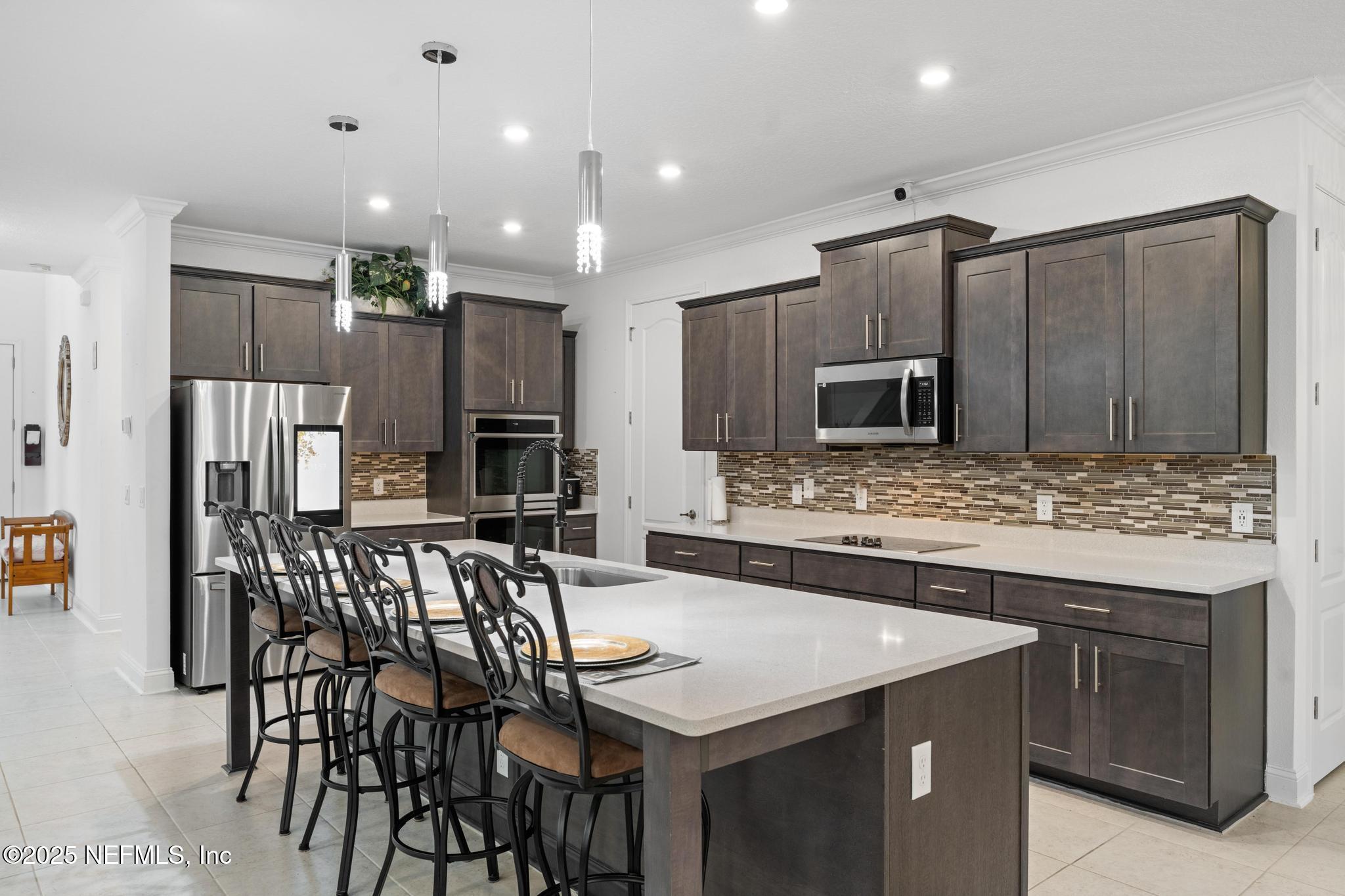 1465 Lake Foxmeadow Road Middleburg, FL 32068 - Photo 8 of 45 a kitchen with stainless steel appliances kitchen island granite countertop a kitchen island and chairs in it