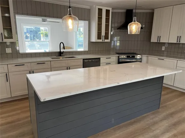 a kitchen with kitchen island granite countertop a sink a counter space and cabinets