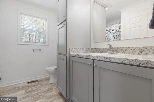a bathroom with a granite countertop sink toilet and mirror