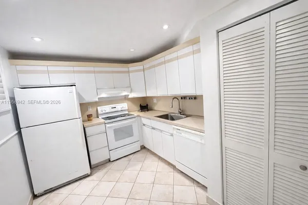 a kitchen with a sink a refrigerator and cabinets