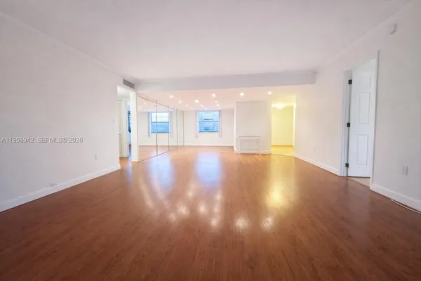 a view of a big room with wooden floor and windows