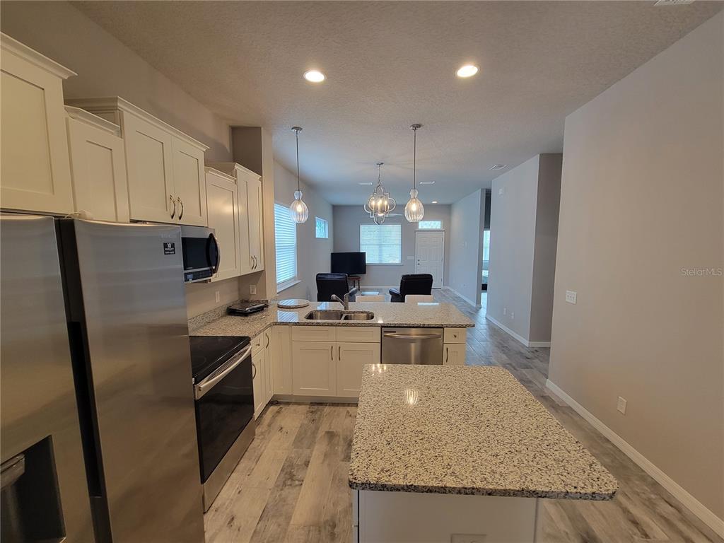 6323 Southwest 47th Terrace Gainesville, FL 32608 - Photo 8 of 25 a kitchen with stainless steel appliances granite countertop a refrigerator a sink dishwasher a stove and white countertops with wooden floor