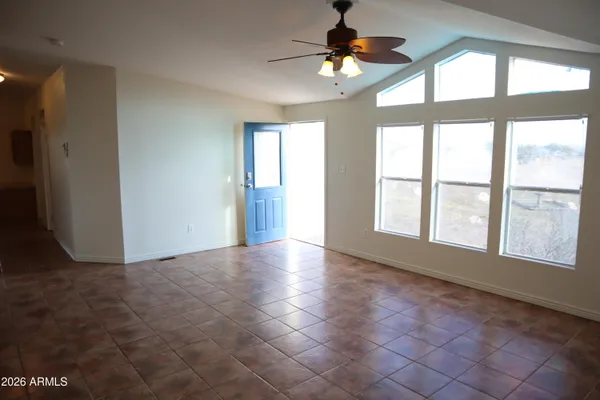 an empty room with chandelier fan and windows