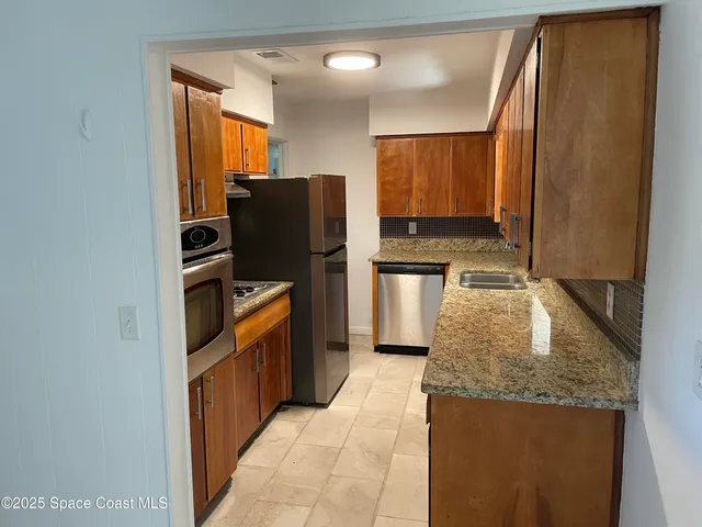 a kitchen with stainless steel appliances granite countertop a refrigerator and a sink