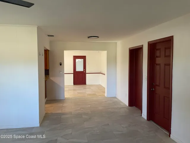 a view of empty room with a window and kitchen view