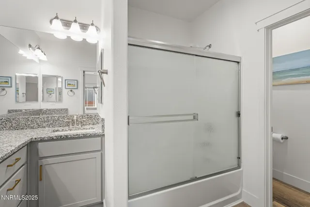a bathroom with a granite countertop shower sink vanity and mirror