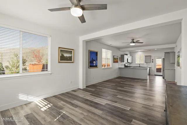 a view of a livingroom with wooden floor and a kitchen