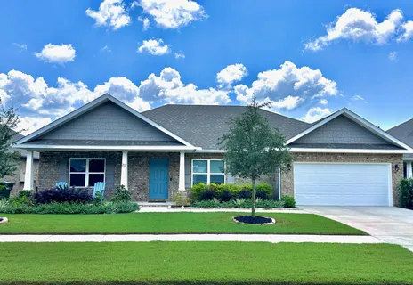a view of a house with a big yard and large tree