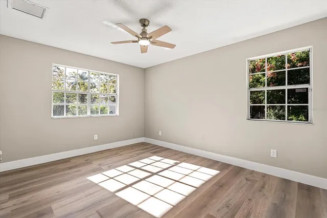 a view of an empty room with wooden floor and window