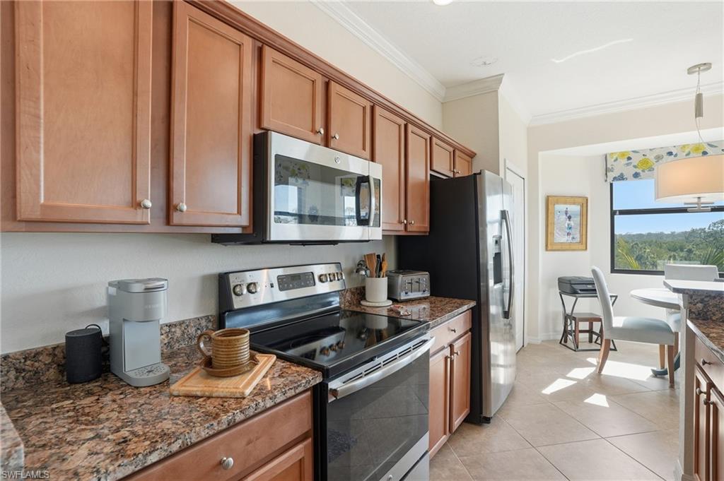 9830 Giaveno Circle, Unit 1646 Naples, FL 34113 - Photo 14 of 30 a kitchen with stainless steel appliances granite countertop a stove a sink and a microwave
