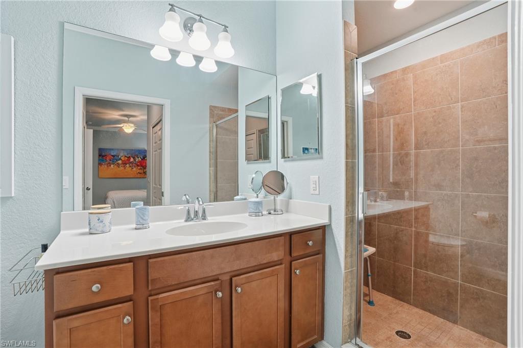 9830 Giaveno Circle, Unit 1646 Naples, FL 34113 - Photo 19 of 30 a bathroom with a sink vanity granite shower and a mirror
