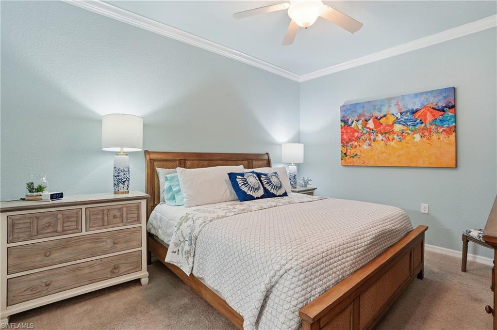 9830 Giaveno Circle, Unit 1646 Naples, FL 34113 - Photo 21 of 30 a bedroom with a bed and a chandelier