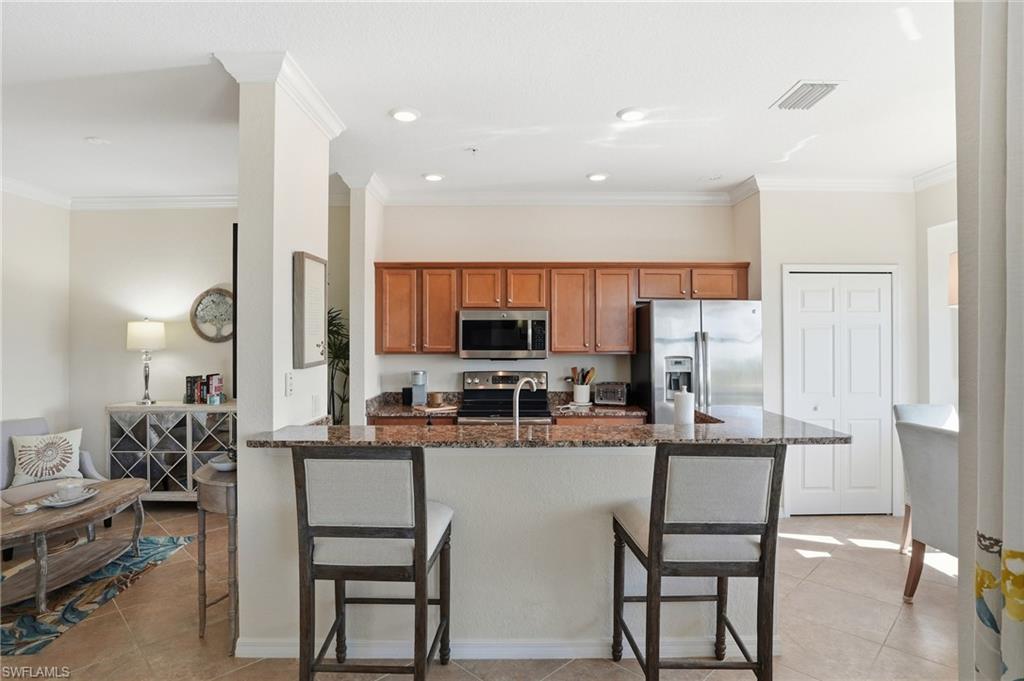 9830 Giaveno Circle, Unit 1646 Naples, FL 34113 - Photo 4 of 30 a dining hall with stainless steel appliances a dining table and chairs