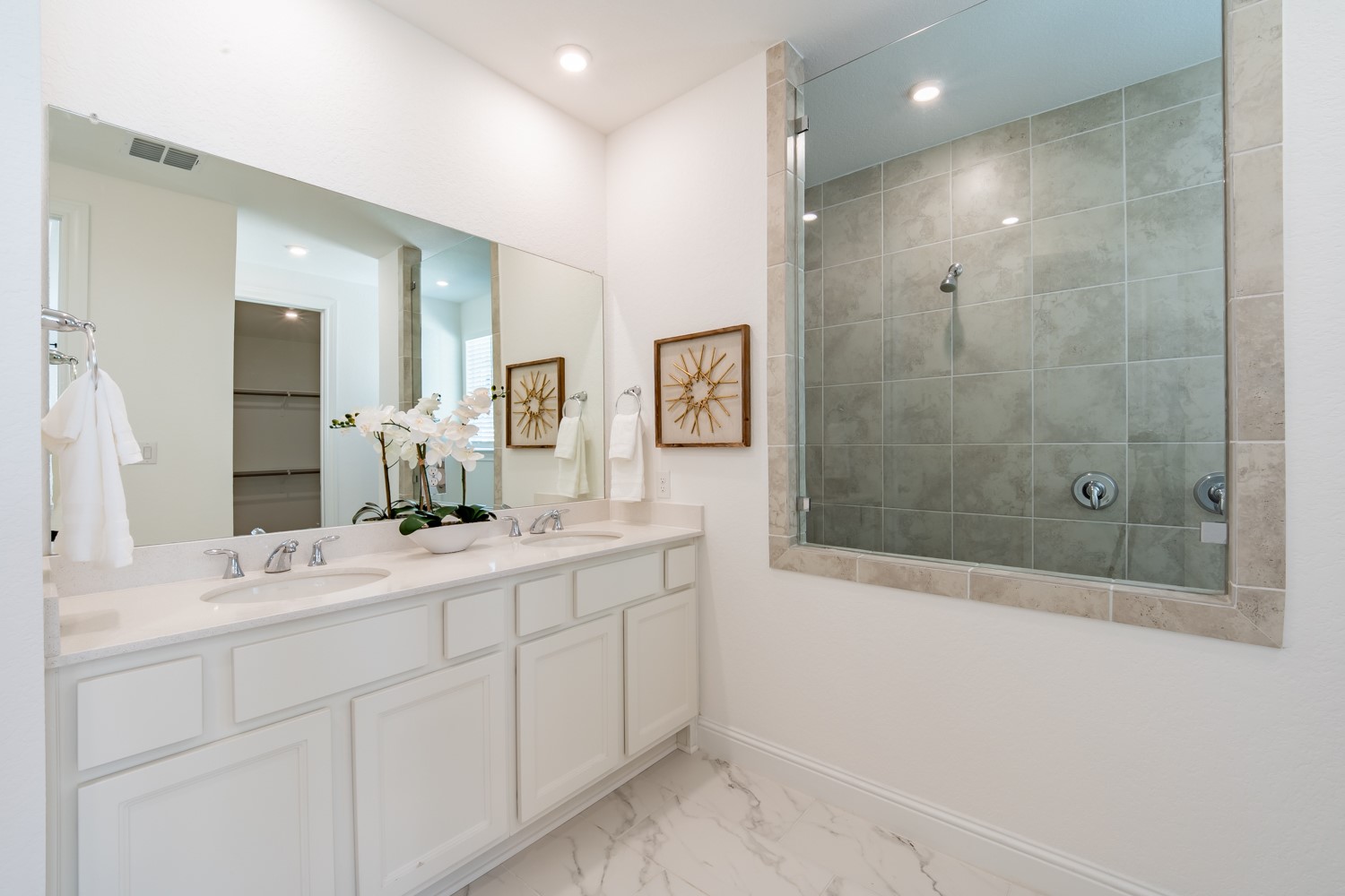 1040 Villa Rialto View Leander, TX 78641 - Photo 22 of 24 Elegant primary bathroom featuring a double vanity, pristine white cabinetry, and a spacious glass-enclosed shower.