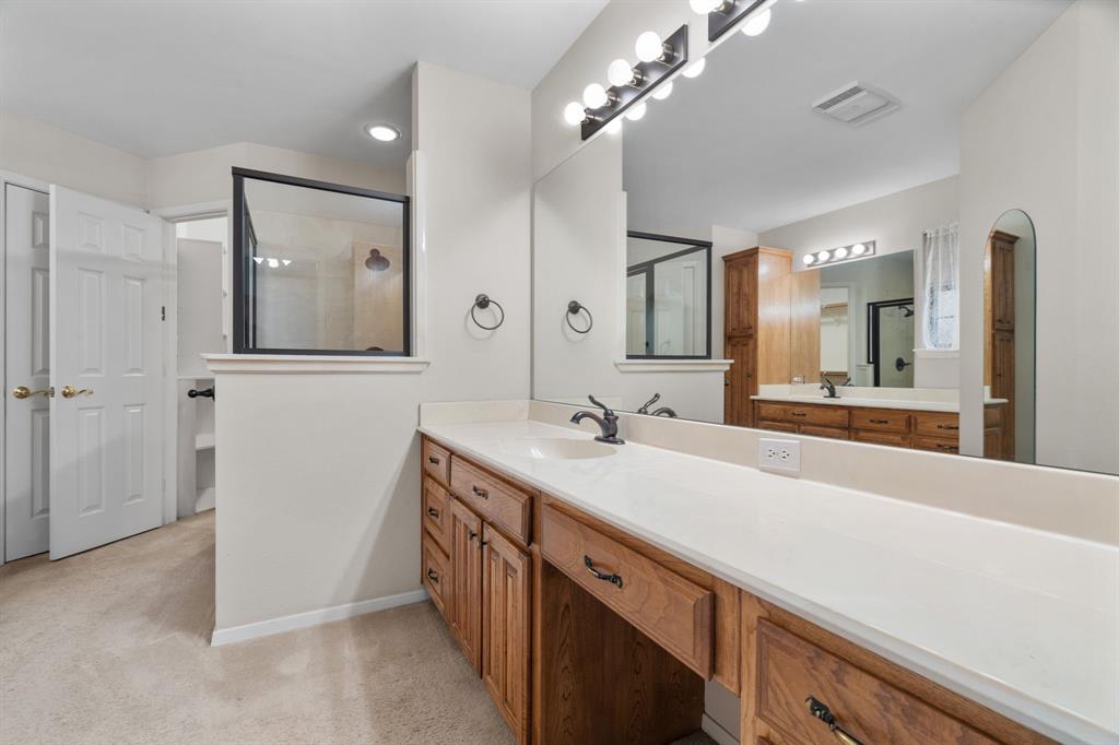 1317 Timber Ridge Road Weatherford, TX 76088 - Photo 16 of 40 a spacious bathroom with a double vanity sink a large mirror and a shower