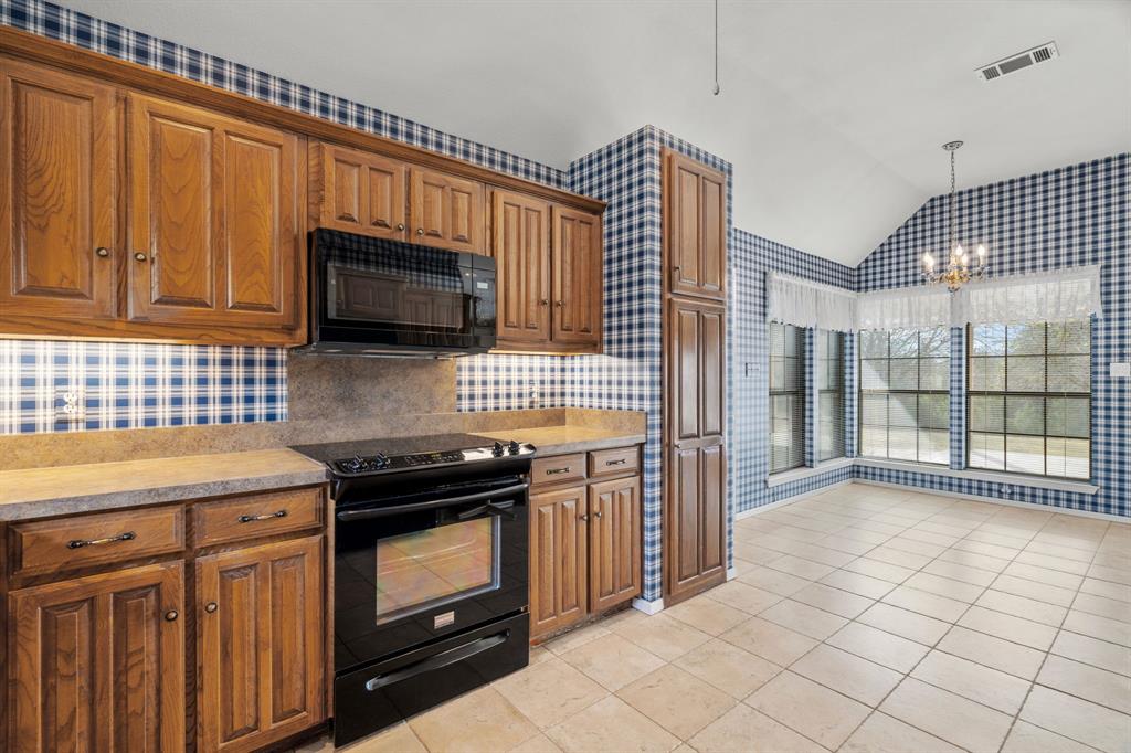 1317 Timber Ridge Road Weatherford, TX 76088 - Photo 9 of 40 a kitchen with granite countertop a stove a sink and a microwave