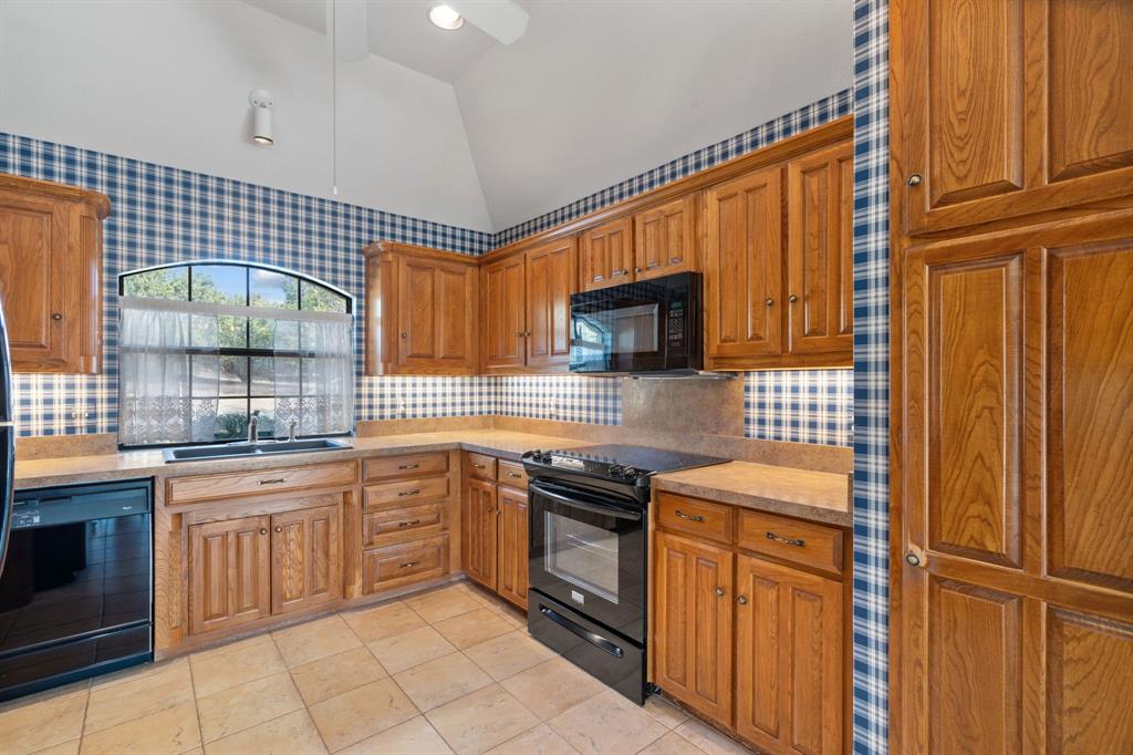 1317 Timber Ridge Road Weatherford, TX 76088 - Photo 10 of 40 a kitchen with stainless steel appliances granite countertop a sink stove and refrigerator