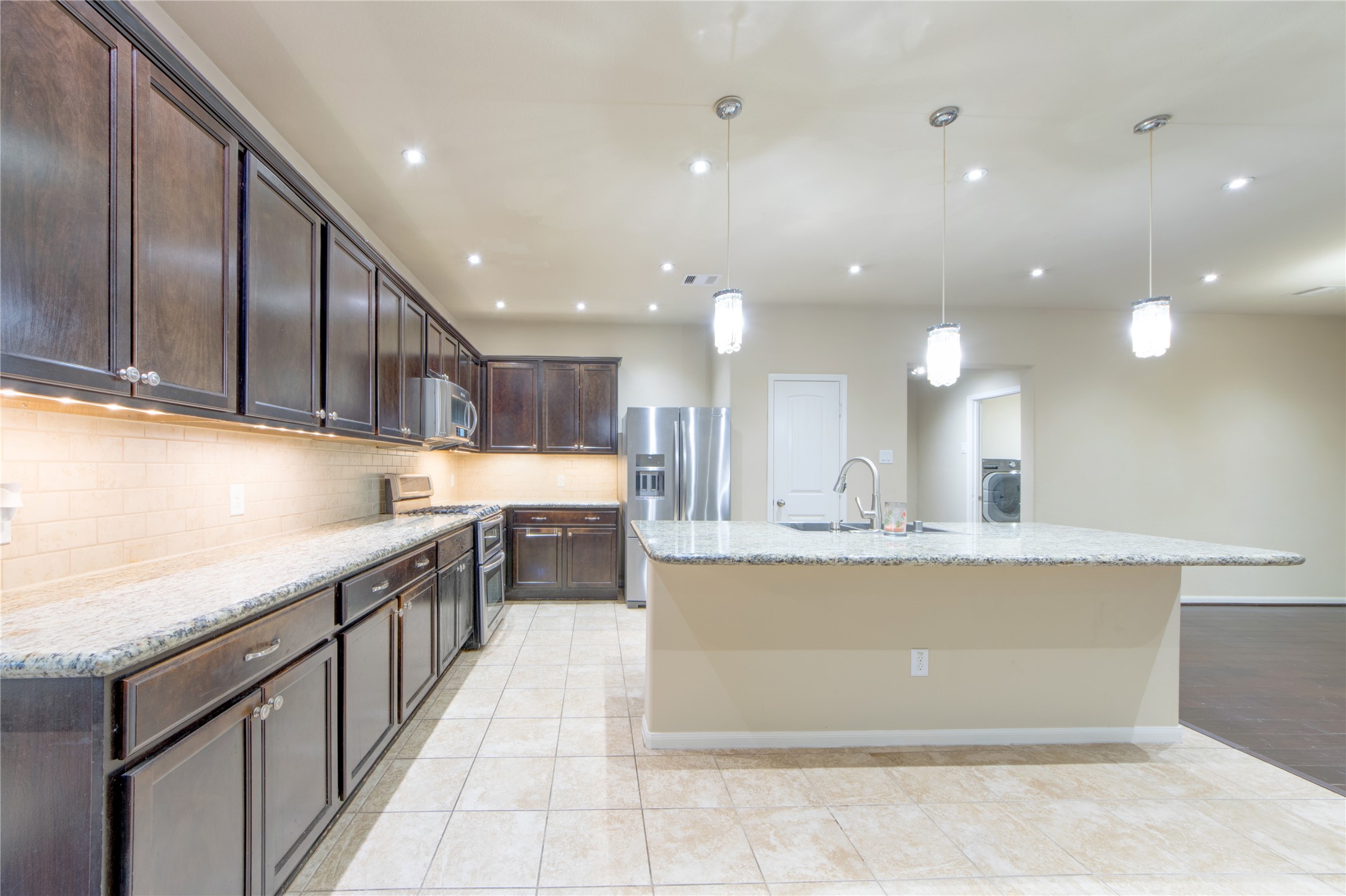 9322 Limestone Ranch Lane Richmond, TX 77407 - Photo 12 of 40 a large kitchen with stainless steel appliances granite countertop a large counter top a stove and a sink
