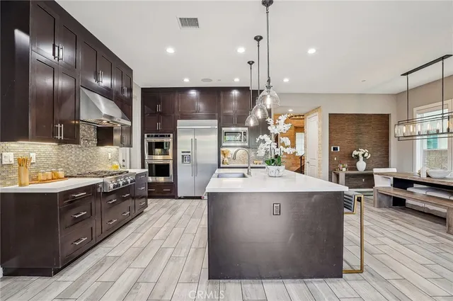 a large kitchen with stainless steel appliances kitchen island granite countertop a large stove a refrigerator a sink and dishwasher with wooden floor