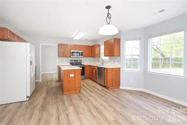 a kitchen with stainless steel appliances granite countertop a stove a sink dishwasher a refrigerator and a dining table with wooden floor