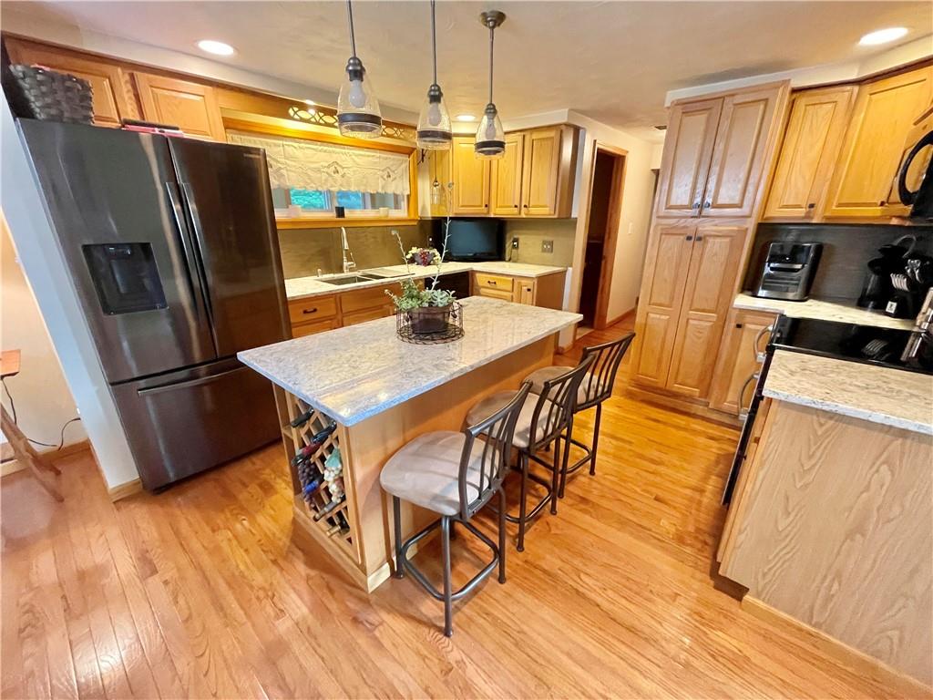 1324 G I Road Spring Church, PA 15686 - Photo 8 of 31 a kitchen with stainless steel appliances a stove a refrigerator a sink a dining table and chairs with wooden floor