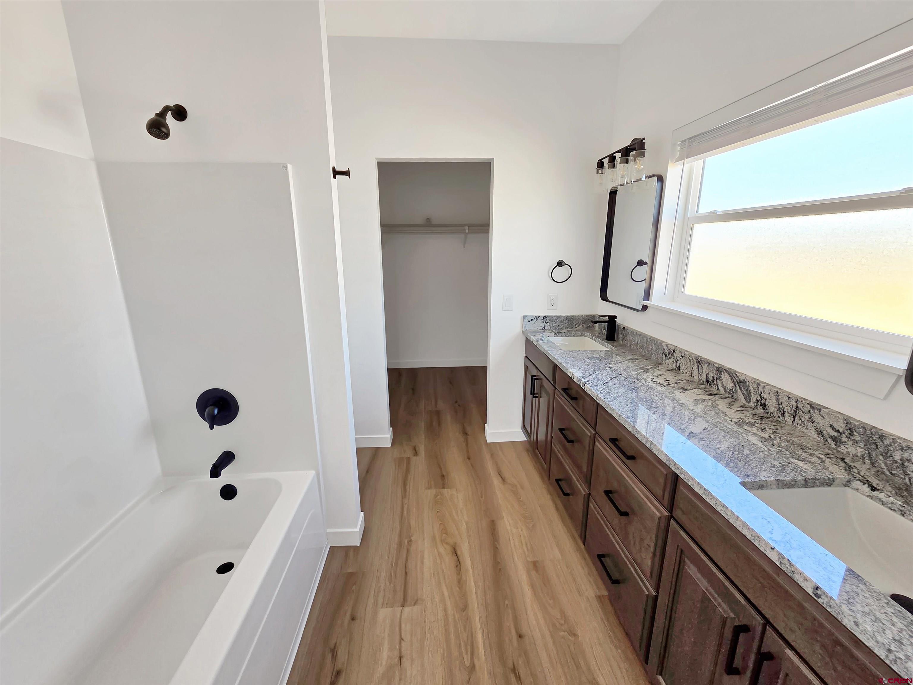 1456 Acoma Street Cortez, CO 81321 - Photo 12 of 26 a spacious bathroom with a granite countertop sink a mirror a bathtub and shower
