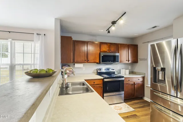 a kitchen with stainless steel appliances granite countertop a refrigerator a stove and a sink with wooden floor
