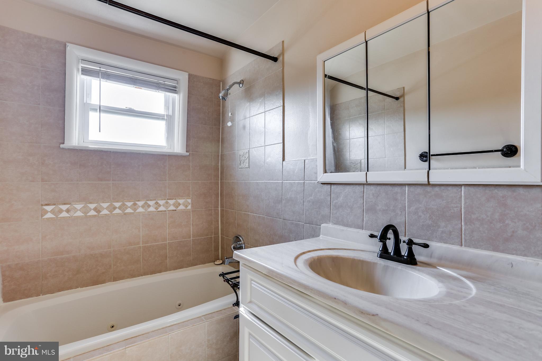 6117 Edlynne Road Baltimore, MD 21239 - Photo 15 of 18 a bathroom with a sink a mirror and a bathtub
