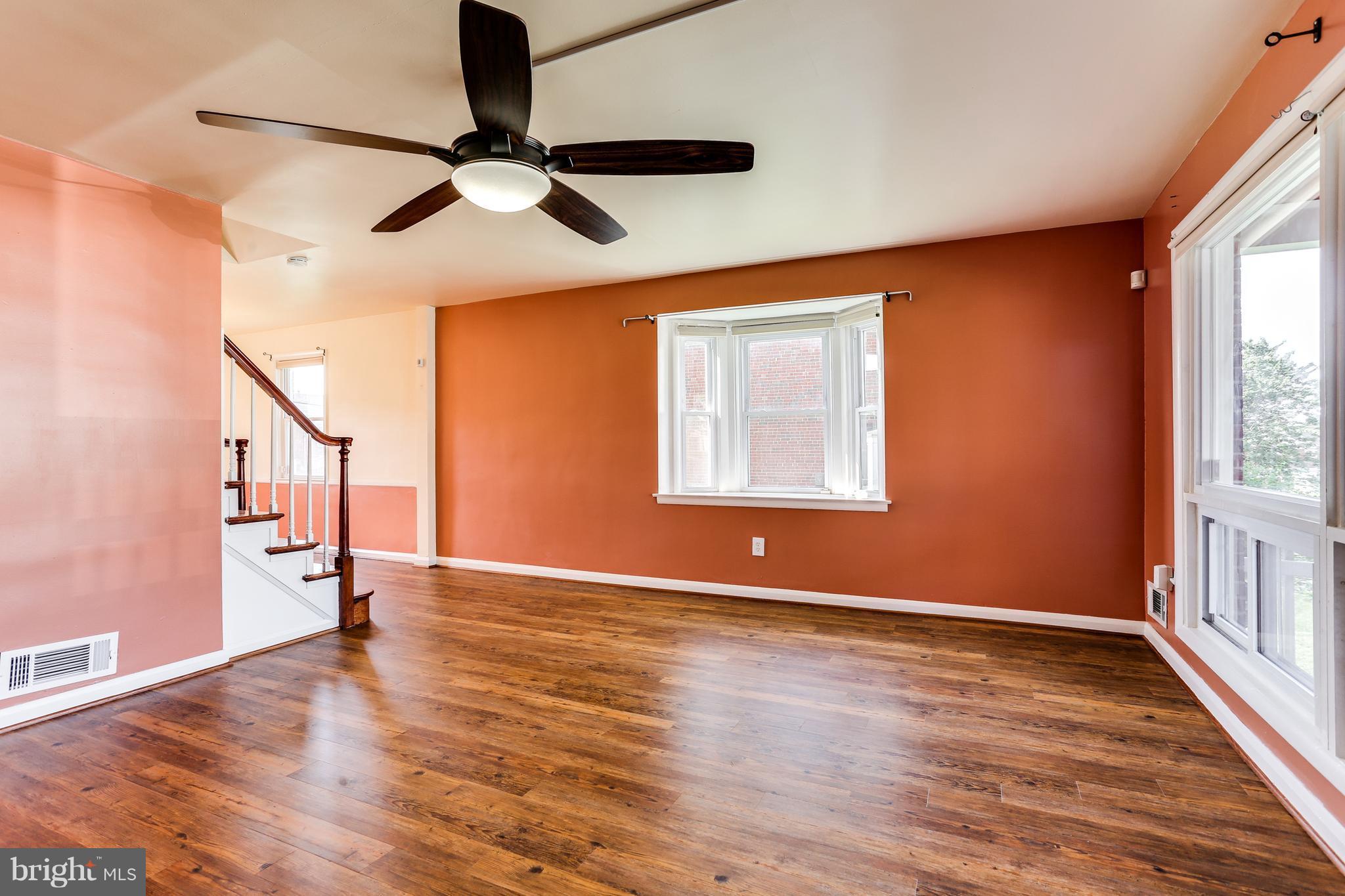 6117 Edlynne Road Baltimore, MD 21239 - Photo 7 of 18 a view of an empty room with wooden floor and a window