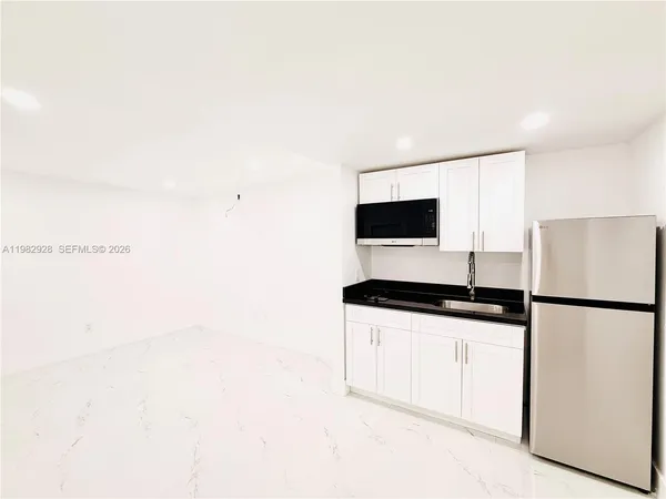 a kitchen with granite countertop white cabinets and white appliances