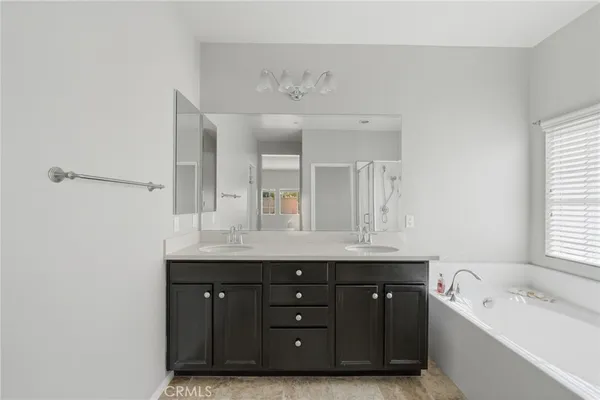 a bathroom with a double vanity sink and mirror with bathtub